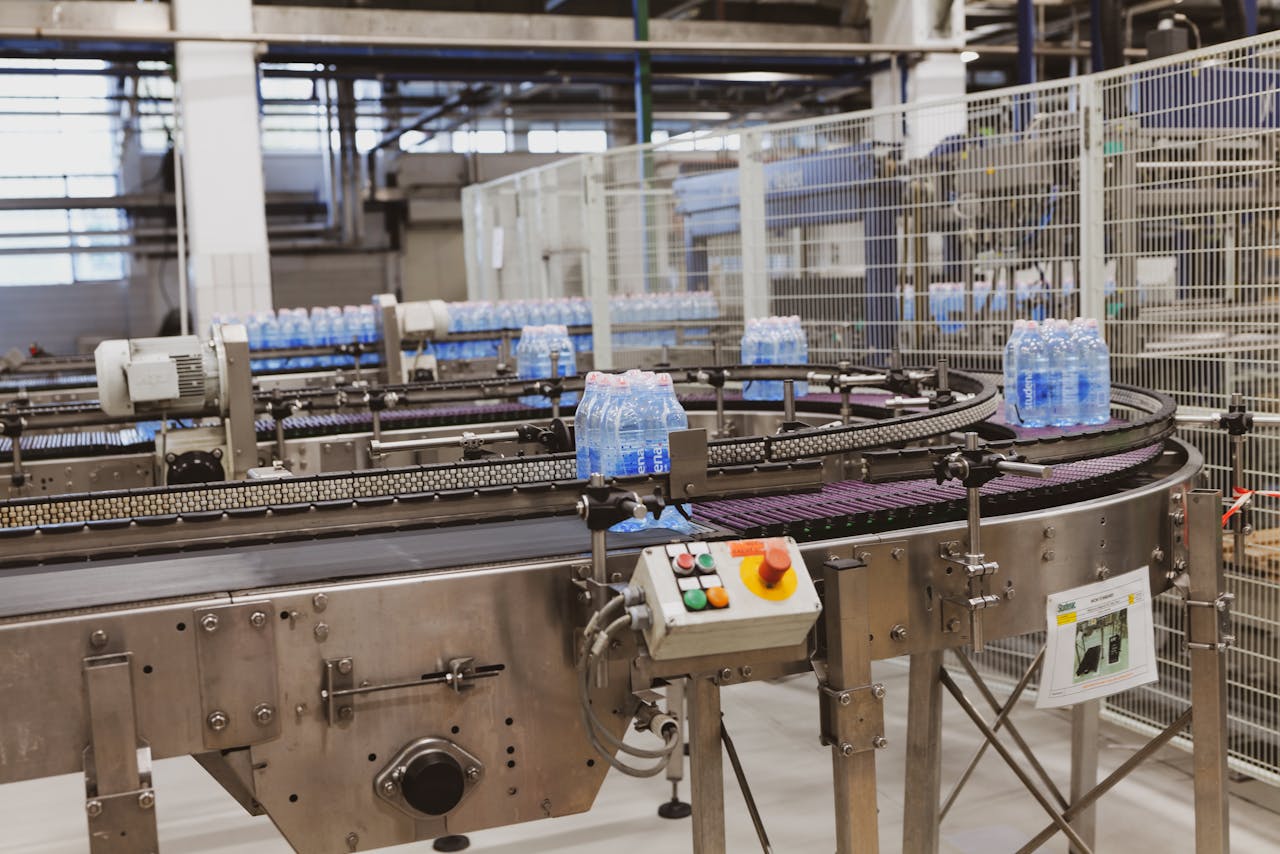 Services Water bottles being processed on an automated conveyor in a modern factory setting.